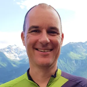 Portraitfoto von lächelndem Mann mit Bergpanorama im Hintergrund